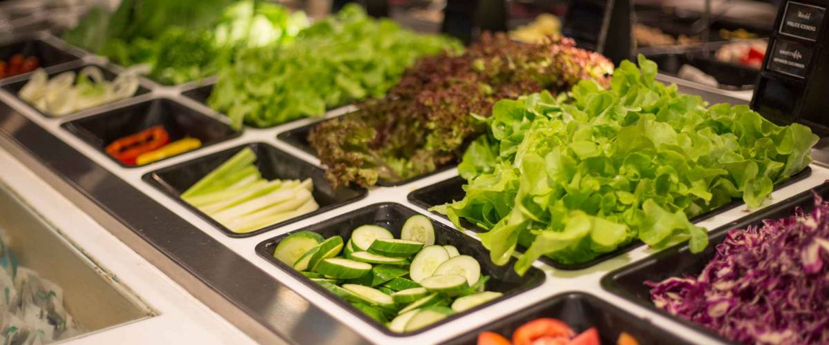 Close up salad bar with various fresh vegetables at supermarket.