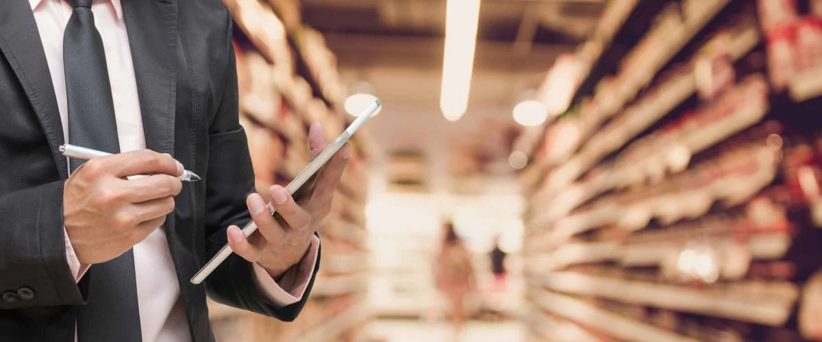 Businessman using the tablet and writing the order stock on Supermarket blur background, business technology concept