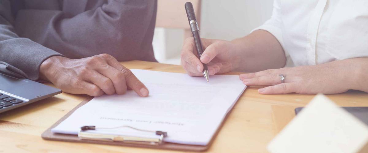 woman's hand hold ballpoint pen writing on  agreement paper sheet, fill in document template, applying for mortgage loan