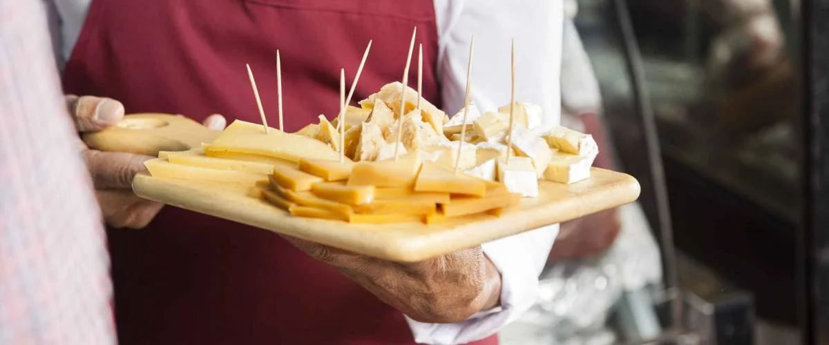 Salesman Holding Cutting Board With Assorted Cheese