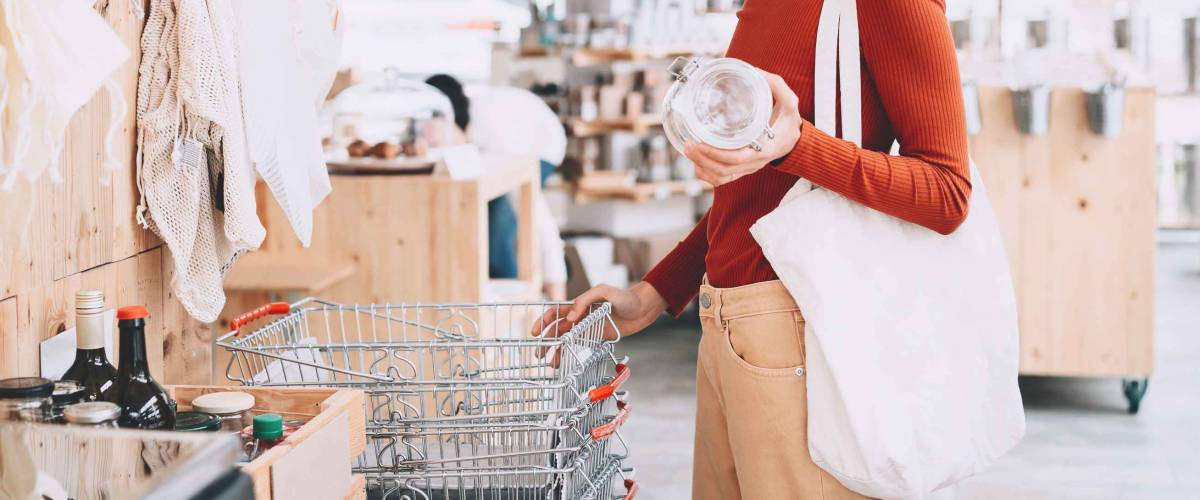 Young woman with reusable cotton bag and empty jar