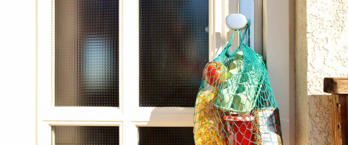 Shopping bag with Merchandise, goods and food is hanging at the front door