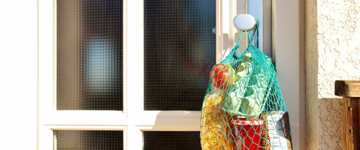 Shopping bag with Merchandise, goods and food is hanging at the front door