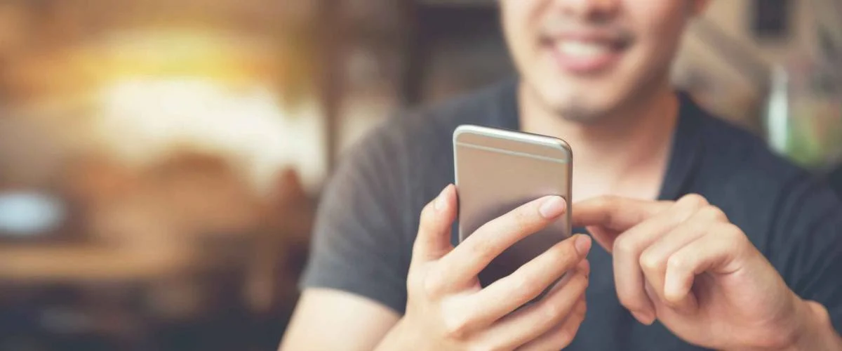 Happy male using smartphone at modern coffee shop, he chatting Online Messaging on mobile.