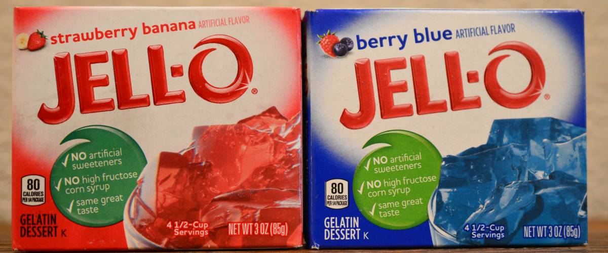 Norman, OK July 20, 2018 A box of strawberry and berry blue Jell-O on a wooden table with a white background