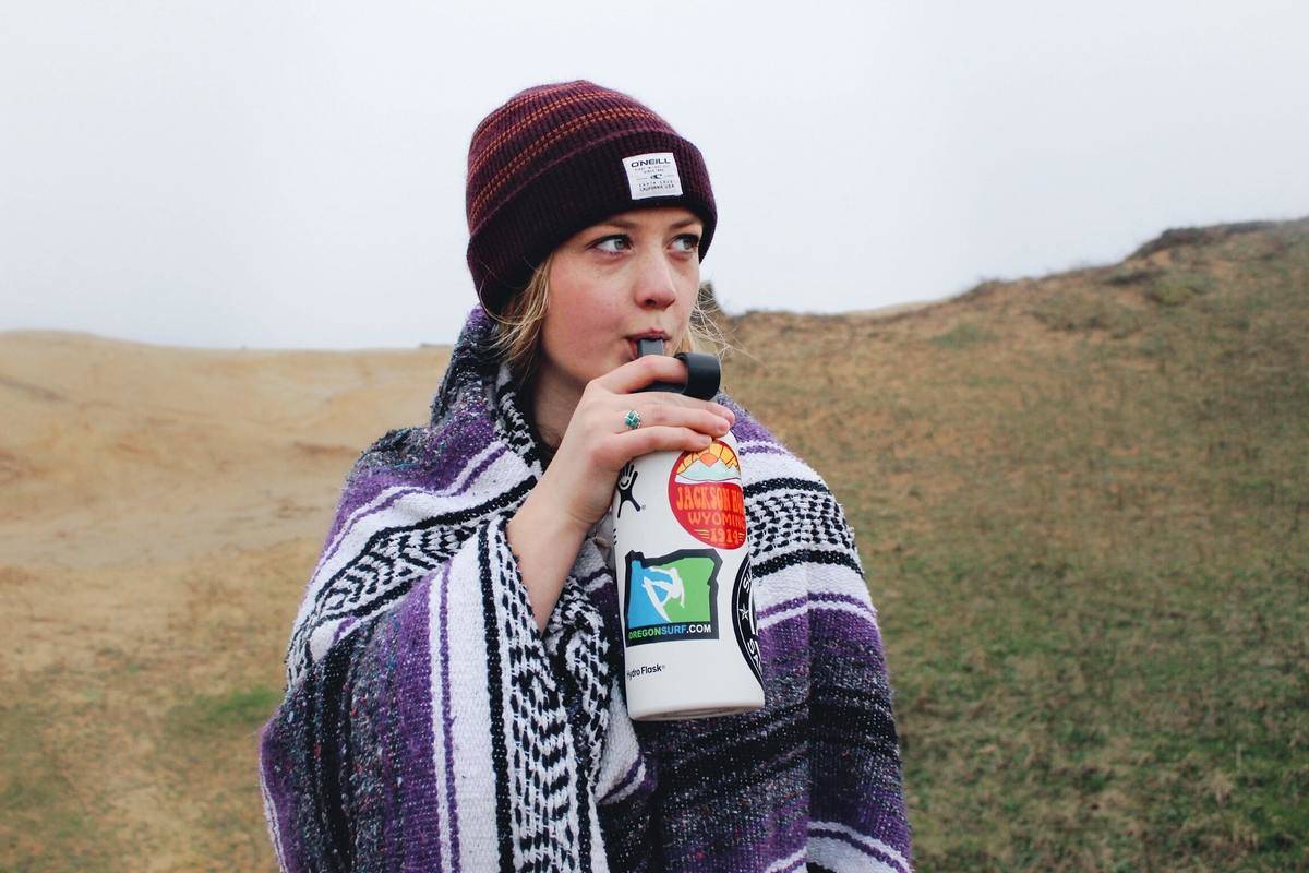 a young woman drinking water out of a reusable water bottle