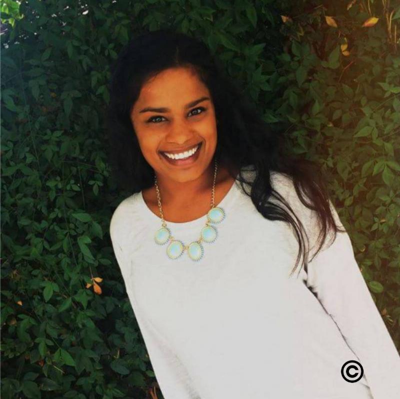 Annie smiling beside a tree