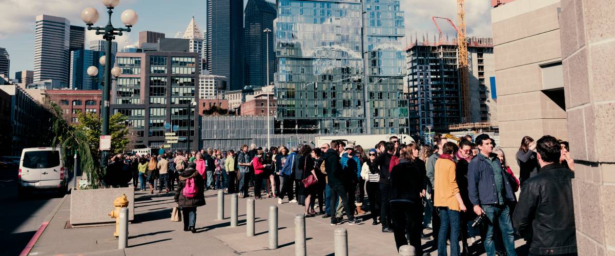 Long line of people waiting to get into an event in downtown Seattle with skyline in the background