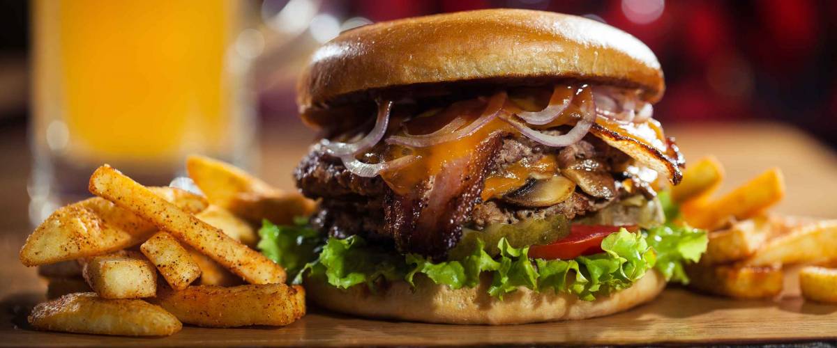 Big tasty burger and fries with beer on background on the wooden table